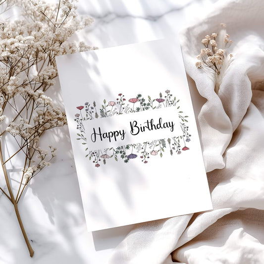 Elegant floral birthday card design featuring hand-drawn wildflowers in pink and purple. Modern calligraphy 'Happy Birthday' text surrounded by delicate botanical illustrations